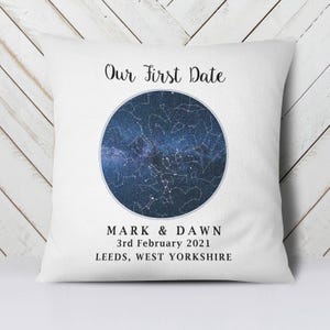 Peut inclure: Coussin carré blanc avec le texte "Our First Date" en écriture noire. Une image circulaire d'un ciel étoilé est au centre. En dessous, les noms "MARK & DAWN", la date "3rd February 2021" et le lieu "LEEDS, WEST YORKSHIRE".
