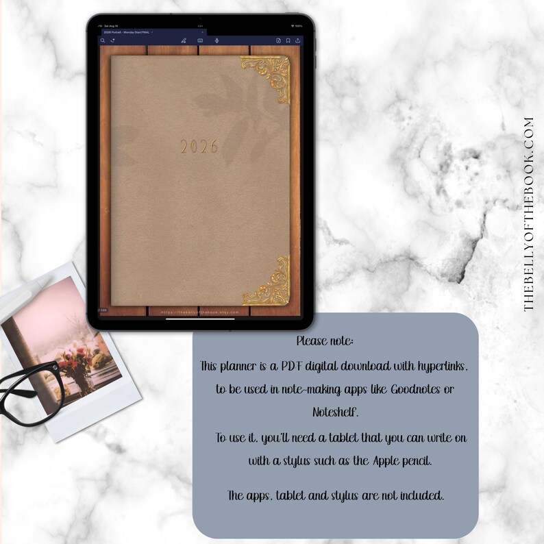 May include: Digital planner displayed on a tablet, featuring a tan cover with the year "2026" and decorative gold corners. The tablet rests on a wooden frame. A note on the side explains the planner is a PDF download.