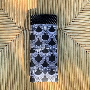 May include: Black fabric eye mask with a white design of a collar. The fabric has a white polka dot pattern on the top edge.