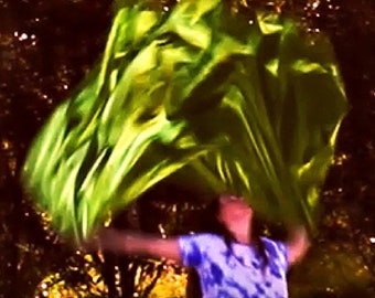 May include: A person is holding a bright green fabric in the air, with their arms outstretched. The fabric is flowing in the wind, creating a dynamic and colorful image.