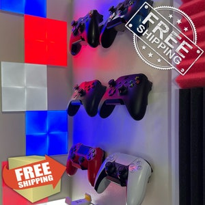 May include: Several video game controllers in black, red, and white are mounted on a wall. The controllers are displayed on individual wall mounts. The wall is lit with red and blue LED lights, and there are decorative light panels.