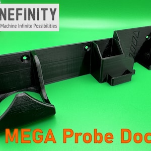 Puede incluir: Un soporte de pared negro impreso en 3D con el texto "MEGA Probe Dock!" impreso debajo. El soporte tiene varios compartimentos para guardar diversos objetos.