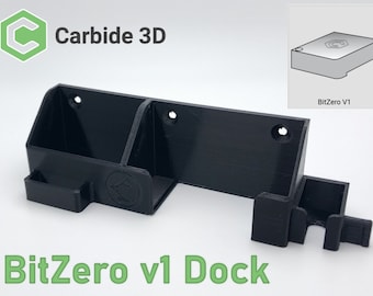 May include: A black 3D printed dock for a BitZero v1 computer. The dock has a slot for the computer and a hook for a cable. The dock is labeled "BitZero v1 Dock" in green text.