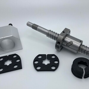 Op de afbeelding: Een zilveren metalen moer met een schroefdraadstang, twee zwarte rubberen ringen en een zilveren metalen koppeling. De moer heeft een zeshoekige vorm en de stang is voorzien van een fijne schroefdraad.