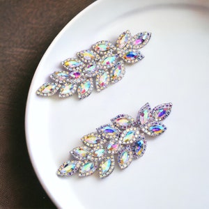 May include: Two iridescent crystal leaf-shaped embellishments on a white background. The crystals are arranged in a cascading pattern, creating a delicate and elegant design.