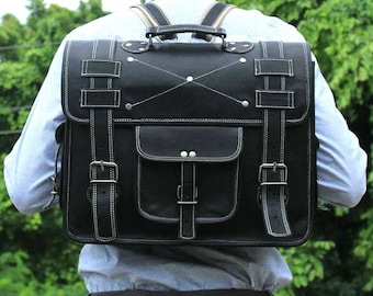 May include: A black leather backpack with white stitching and silver buckles. The backpack has a large main compartment and a smaller front pocket.