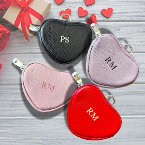 May include: Four heart-shaped zippered pouches with gold zippers and personalised initials. The pouches are black, pink, red, and light pink.