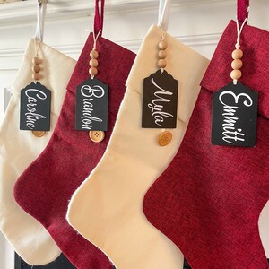 May include: Four red and cream-colored Christmas stockings with black name tags that read "Caroline", "Brandon", "Myla", and "Emmitt".