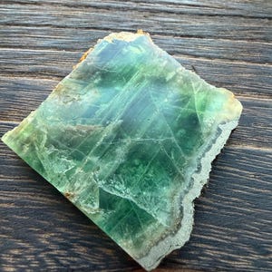 Może przedstawiać: Zestaw trzech ceramicznych kubków z nakrapianym, matowym wykończeniem. Kubki są w odcieniach kremu, jasnoszarym i ciemnoszarym. Każdy kubek ma prosty, minimalistyczny design, idealny do kawy lub herbaty.