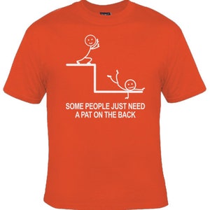 May include: Orange t-shirt featuring a white stick figure design. The design depicts one stick figure pushing another stick figure off a ledge. The text reads "Some people just need a pat on the back."