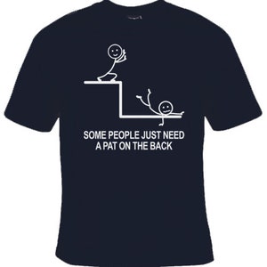 May include: A dark blue t-shirt featuring a white stick figure design. The design depicts one stick figure pushing another stick figure off a ledge. The text on the shirt reads "Some people just need a pat on the back."