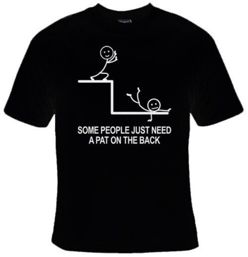 May include: Black t-shirt featuring a white stick figure design. The stick figure is falling off a ledge and another stick figure is reaching down to help. The text reads "Some people just need a pat on the back."