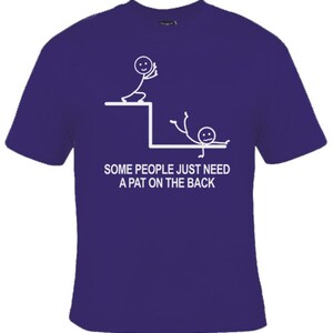 May include: A purple t-shirt featuring a white stick figure design. The design depicts one stick figure pushing another stick figure off a ledge. The text on the shirt reads "Some people just need a pat on the back."