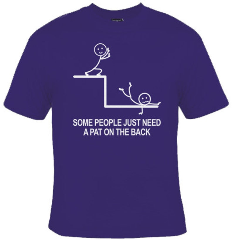 May include: A purple t-shirt featuring a white stick figure design. The design depicts one stick figure pushing another stick figure off a ledge. The text on the shirt reads "Some people just need a pat on the back."