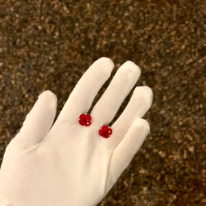 May include: A pair of red flower-shaped earrings with clear crystal accents.
