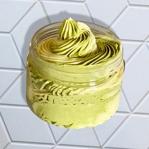 May include: A glass jar filled with a green and white whipped body butter. The butter is swirled and has a smooth, creamy texture.