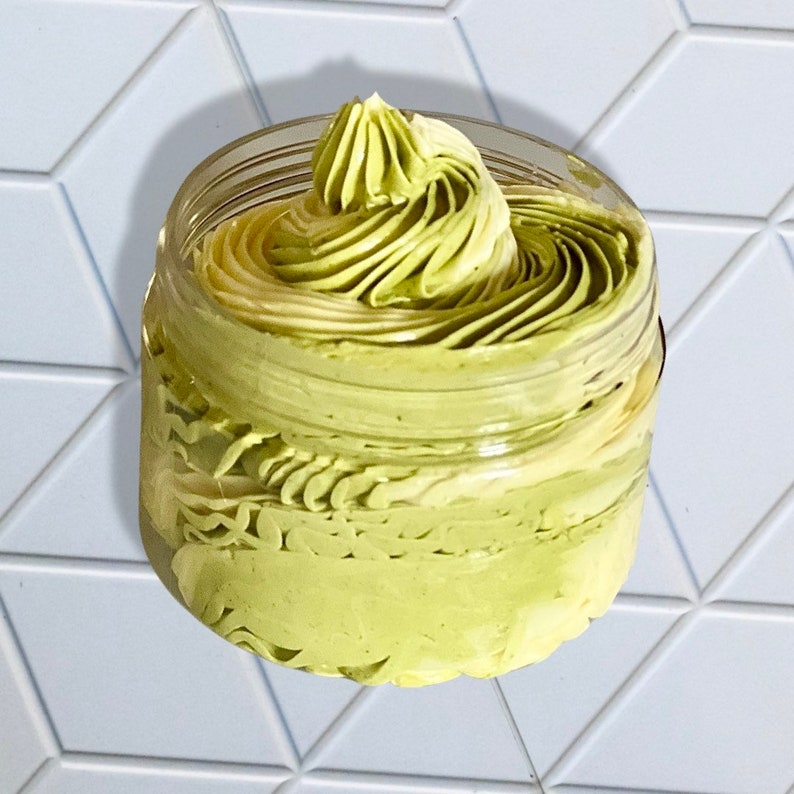 May include: A glass jar filled with a green and white whipped body butter. The butter is swirled and has a smooth, creamy texture.