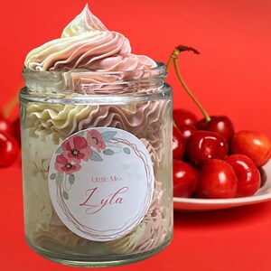 May include: A glass jar filled with a pink and white whipped body butter. The jar has a round sticker with a floral design and the text "Little Miss Lyla".