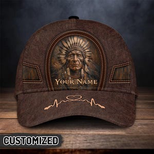 May include: Brown baseball cap with a detailed Native American chief design. The cap features the text "YOUR NAME" and a heartbeat line with a heart symbol. The word "CUSTOMIZED" is printed at the bottom.