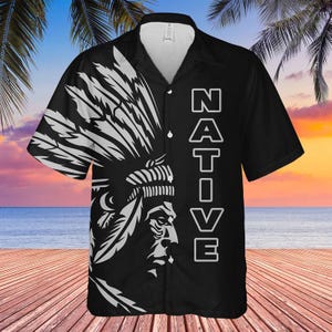 May include: Black button-up shirt with a white Native American headdress design on the left side. The word "NATIVE" is printed vertically in white on the right side. The shirt has short sleeves and a collared neckline.