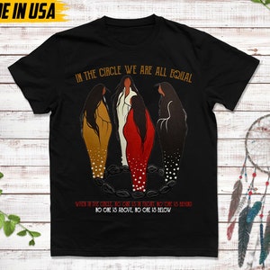 Puede incluir: Camiseta negra con el texto "IN THE CIRCLE WE ARE ALL EQUAL" y una ilustraci&oacute;n de tres figuras en c&iacute;rculo. El texto "WHEN IN THE CIRCLE, NO ONE IS IN FRONT, NO ONE IS BEHIND, NO ONE IS ABOVE, NO ONE IS BELOW" tambi&eacute;n est&aacute; impreso en la camiseta. "MADE IN USA" est&aacute; impreso en la parte superior izquierda.