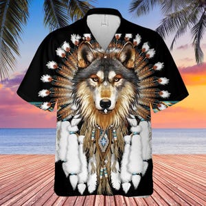 May include: Black button-up shirt featuring a detailed wolf design with feathers and tribal elements. The wolf has brown and gray fur, with a white and blue patterned design on the chest. The shirt has short sleeves.