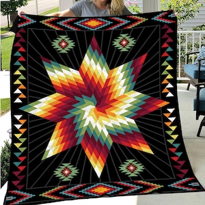K&ouml;nnte beinhalten: Eine schwarze Steppdecke mit einem lebendigen geometrischen Sternmuster in Rot-, Orange-, Gelb-, Gr&uuml;n- und Blaut&ouml;nen. Die Steppdecke hat einen Rand mit sich wiederholenden geometrischen Mustern und Dreiecken. Das Gesamtdesign hat eine indianische &Auml;sthetik.