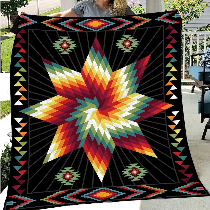 K&ouml;nnte beinhalten: Eine schwarze Steppdecke mit einem lebendigen geometrischen Sternmuster in Rot-, Orange-, Gelb-, Gr&uuml;n- und Blaut&ouml;nen. Die Steppdecke hat einen Rand mit sich wiederholenden geometrischen Mustern und Dreiecken. Das Gesamtdesign hat eine indianische &Auml;sthetik.