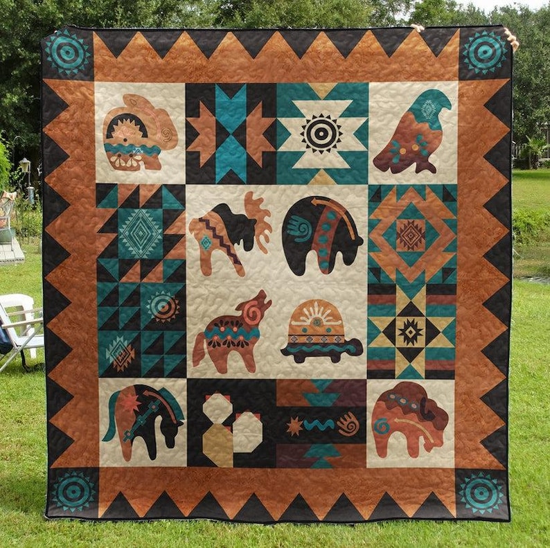 May include: A square quilt with a Native American design. The quilt features a repeating pattern of animal and geometric shapes in shades of brown, teal, black, and cream. Animals include a rabbit, eagle, moose, bear, wolf, turtle, horse, and buffalo.