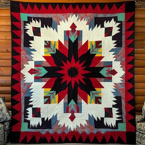 May include: A large, colorful quilt with a central starburst design in red and black. The quilt features geometric patterns in white, teal, yellow, and blue, framed by a red border with black triangles. The quilt is displayed against a wooden wall.