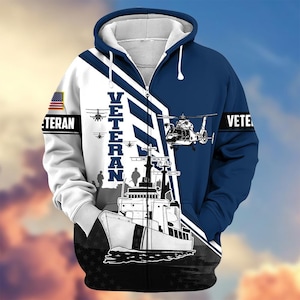 Pode incluir: Um casaco com capuz azul marinho e branco com um design patri&oacute;tico. O casaco com capuz apresenta um navio, helic&oacute;pteros e a palavra "VETERAN" em negrito. Uma bandeira americana &eacute; exibida na manga esquerda.