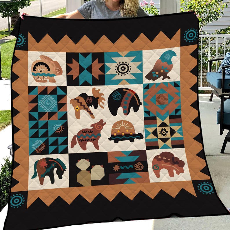 May include: A quilted blanket featuring a Native American design with geometric patterns and animal motifs. The blanket has a black border with a brown and tan geometric pattern. The central design includes a rabbit, moose, wolf, turtle, and other animals.