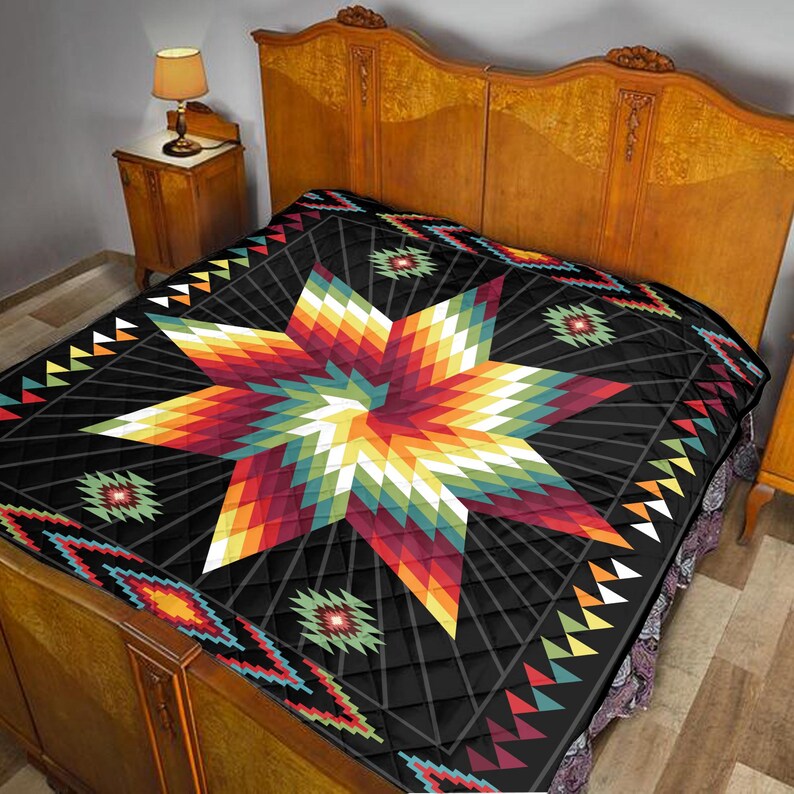 K&ouml;nnte beinhalten: Eine schwarze Steppdecke mit einem gro&szlig;en, farbenfrohen Sternmuster in Rot-, Orange-, Gelb-, Gr&uuml;n- und Wei&szlig;t&ouml;nen. Die Steppdecke hat ein geometrisches Muster und wird auf einem h&ouml;lzernen Bettrahmen pr&auml;sentiert.
