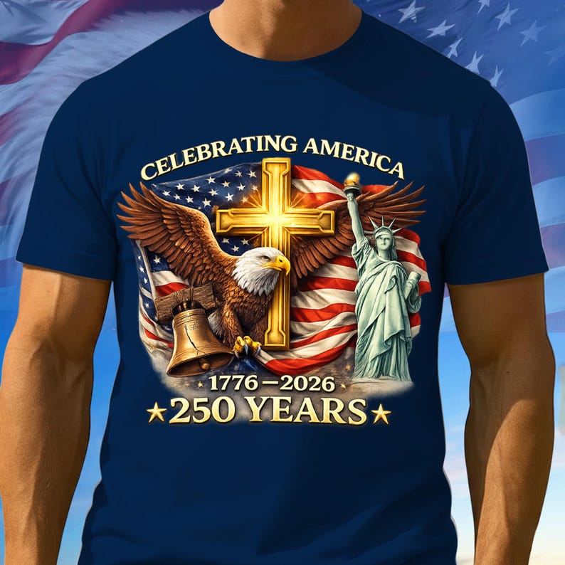 May include: Navy blue t-shirt featuring a patriotic design with an eagle, cross, Statue of Liberty, and American flag. Text reads "CELEBRATING AMERICA" and "1776-2026 *250 YEARS*".