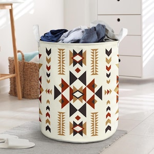 May include: A cream-colored laundry hamper with a geometric pattern in shades of brown, black, and tan. The hamper is filled with folded clothes and has white handles. The design features triangles, diamonds, and arrow shapes.