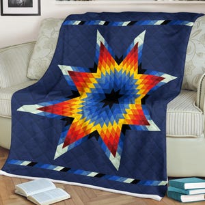May include: A navy blue quilt with a large, colorful starburst design. The star features a geometric pattern in shades of red, orange, yellow, and blue, with a black center. The quilt has a diamond-stitched pattern.