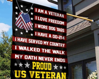 May include: A black and red US Veteran flag with the text "I AM A VETERAN" and "PROUD US VETERAN". The flag features dog tags and a camouflage bottom border. The flag is hanging outside a house.