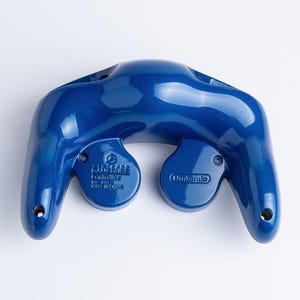 May include: A glossy, dark blue Nintendo GameCube controller shell viewed from the back. The plastic casing features moulded text including the Nintendo logo, the word Controller, and the phrase Made in China, with visible screw holes at the base.
