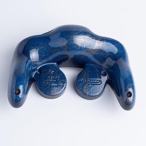 May include: A dark blue video game controller shell with a gold-coloured marbled or distressed finish. The back of the controller features two rounded hand grips and a central section with the embossed Nintendo logo visible on the right side.