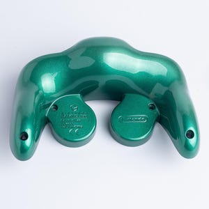 May include: A metallic emerald green Nintendo GameCube controller shell viewed from the back. The plastic casing features a glossy finish with moulded text including Nintendo Controller, model number DOL-003, and Made in China markings.