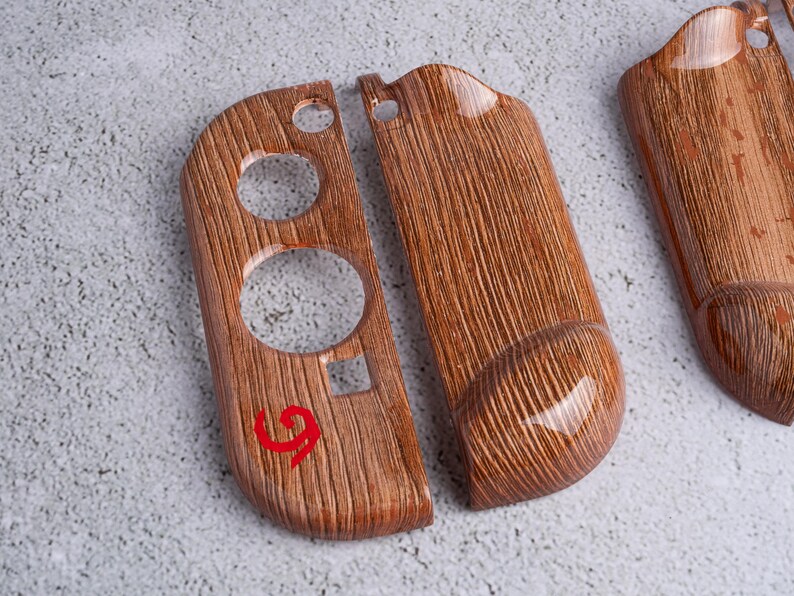 May include: Wooden-textured controller shells with a glossy finish. The shells have a wood grain pattern and a red number 9 is visible on one of the shells. The shells have circular and square cutouts.