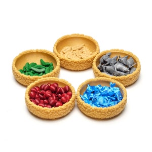 May include: Five small, round, woven baskets filled with different coloured game pieces. The baskets are arranged in a circle on a white background. The pieces include green caterpillars, red berries, blue fish, grey mice, and brown leaves.