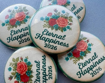 Puede incluir: Varios botones redondos con un diseño floral que presenta rosas rojas y rosas, detalles turquesas y el texto "Eternal Happiness 2026". Los botones tienen un borde verde y un estilo vintage.