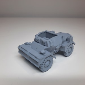 Può includere: Un modello di auto blindata militare in plastica grigia. L'auto ha un tetto aperto rialzato e manca di una torretta per cannoni.