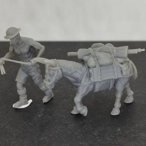以下が含まれることがあります： 灰色のプラスチック製の玩具の兵士のフィギュアが、物資を運ぶ灰色のプラスチック製の玩具のロバを先導しています。ロバは、袋とライフルを積んでいます。