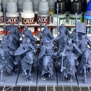 Puede incluir: Colección de figuras en miniatura que representan caballeros esqueléticos montados a caballo. Las figuras son de color azul grisáceo apagado y están montadas sobre bases individuales. Cada caballero está armado con un arma, como una lanza o una espada.