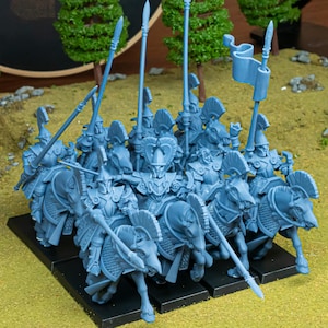 May include: A collection of blue miniature figurines showing mounted warriors with spears and banners. The figures are on horseback, with detailed armour and helmets. The miniatures are arranged on a black base, suggesting a tabletop game.