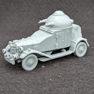 May include: A grey, plastic model of an armoured car with a dome-shaped turret on top. The car has four wheels and a detailed exterior.