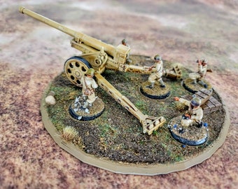 May include: Miniature beige artillery cannon with several miniature soldiers on a circular base. The cannon has a long barrel and a large wheel. The soldiers are in a firing position. The base is covered in grass and dirt.