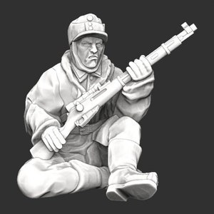 Könnte beinhalten: Graustufen-Skulptur eines Soldaten in Winteruniform, der kniet und ein Gewehr hält. Die Figur trägt eine Mütze, einen schweren Mantel und hohe Stiefel. Das Gesicht des Soldaten zeigt einen strengen Ausdruck.